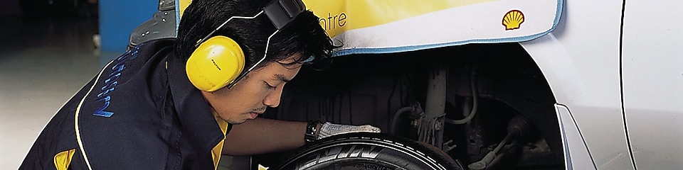 man changing front car tyre at workshop