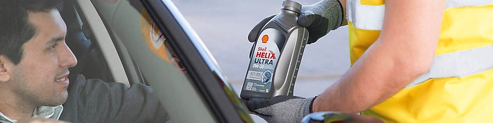 station attendant showing a bottle of shell helix ultra to a man in a car