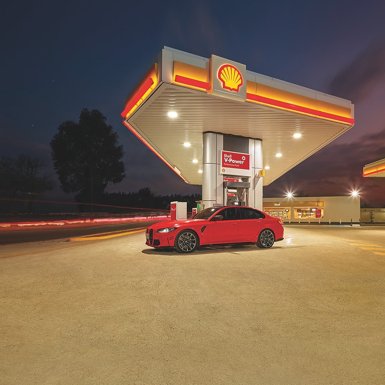A red BWM M3 parked on a Shell Forecourt during dusk