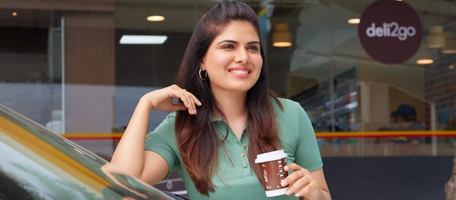 Woman holding a coffe cup near car