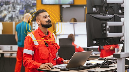 Employee in safety suit is working on machine in factory.
