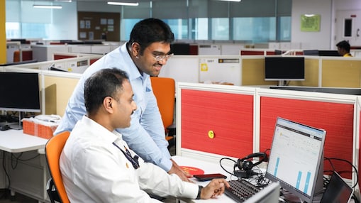 Two co-workers smiling and looking at laptop
