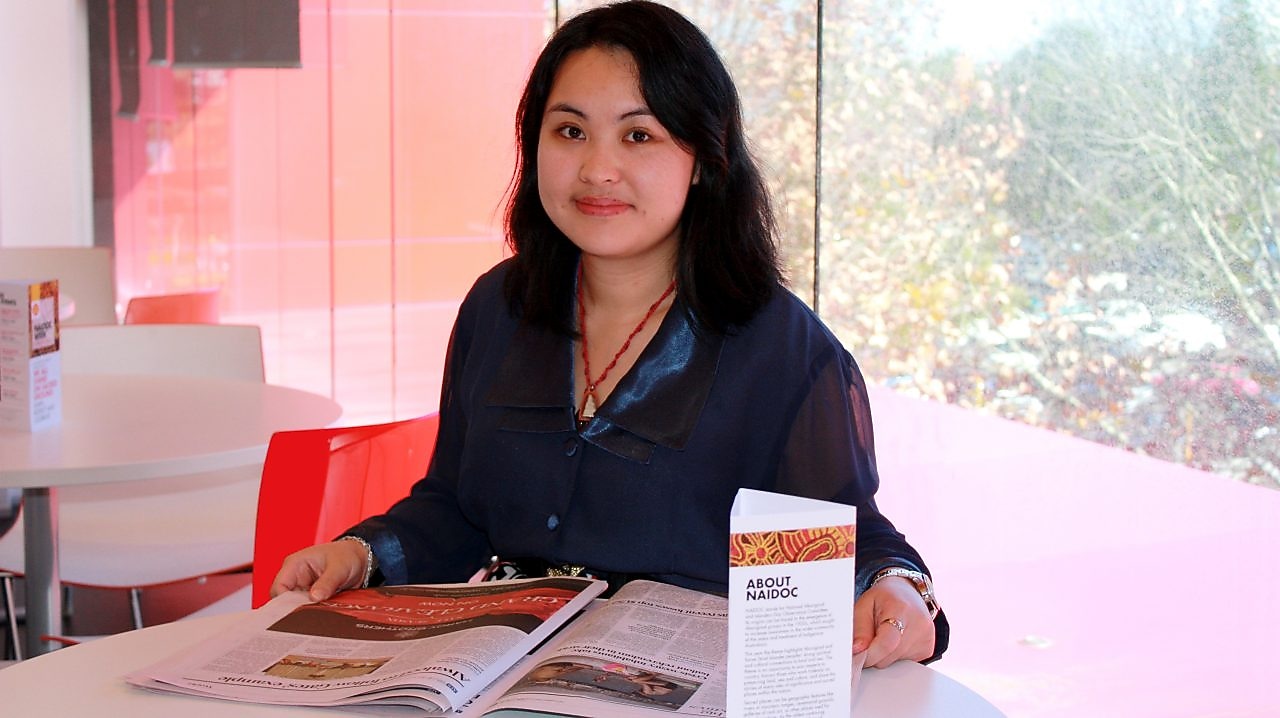 A woman reading newspaper at her desk