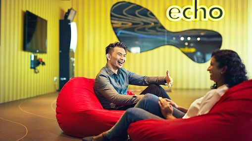Two people seated on red bean bags in a modern office lounge, engaged in conversation.