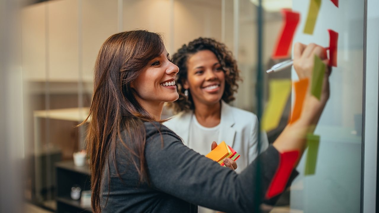 Woman writing on board and smiling