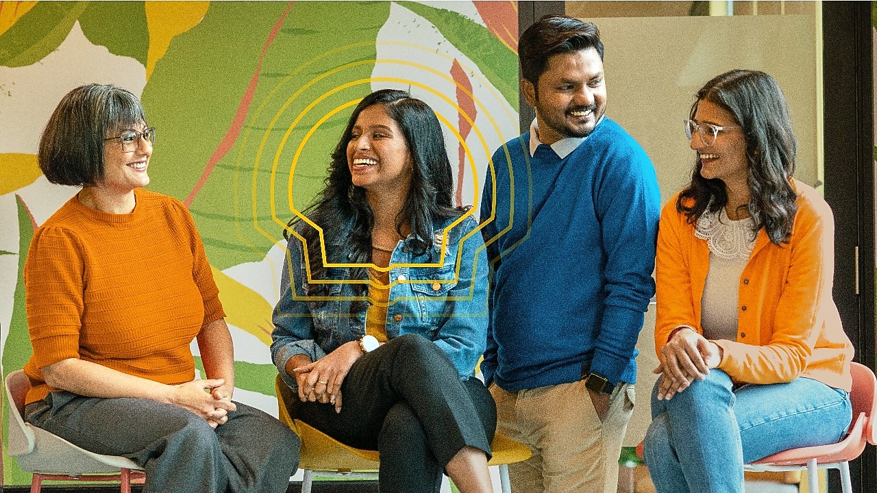 Four colleagues looking at one another and smiling