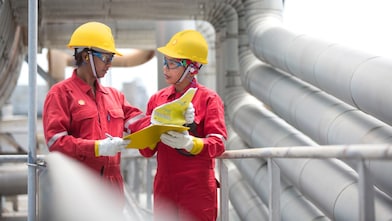Employees on site discussing work and referring to clipboard