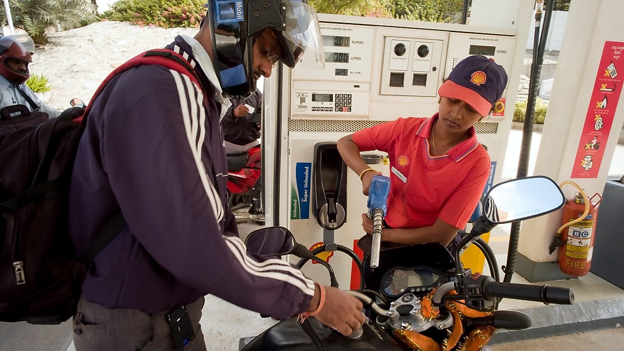 Woman shell attendant helping motorcyclist refuel his motorbike