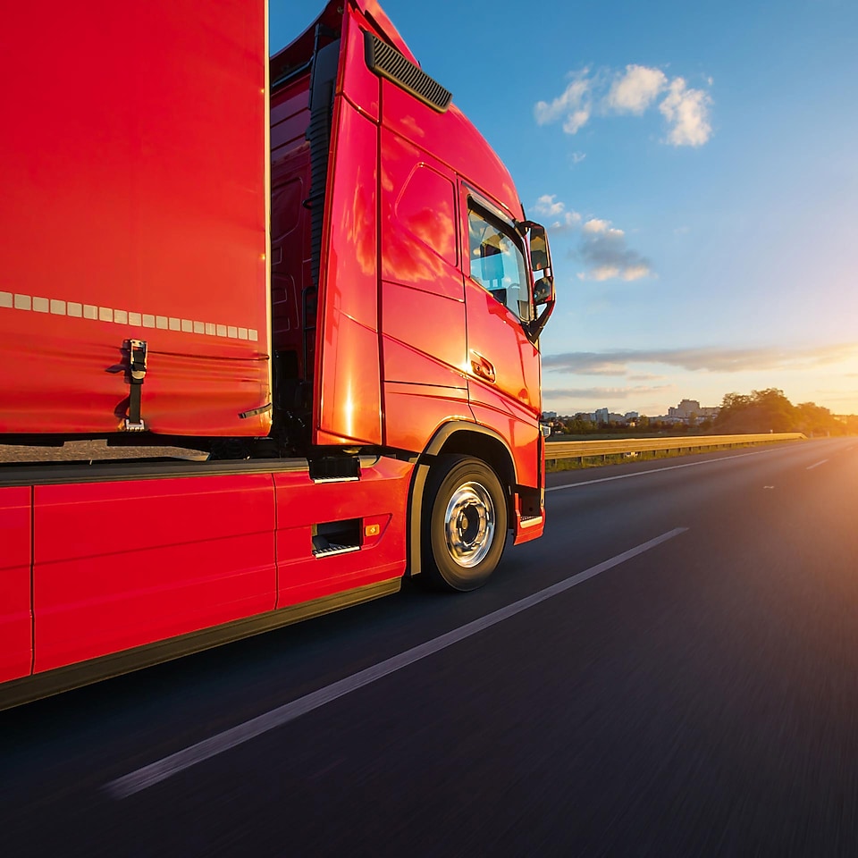 Close up image of red truck, driving towards the sunset
