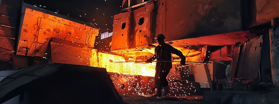 Worker mixing liquid metal in a furnace