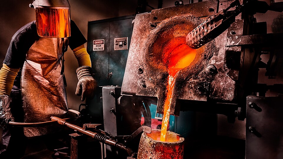 Worker at a furnace pouring melted metal