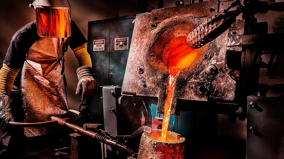 Worker at a furnace pouring melted metal    