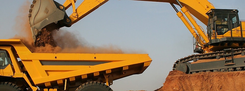 Tracked Excavator loading sediment into a dump truck