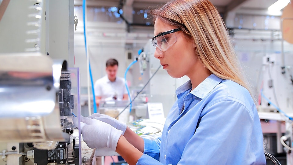 Female factory worker inspecting machinery