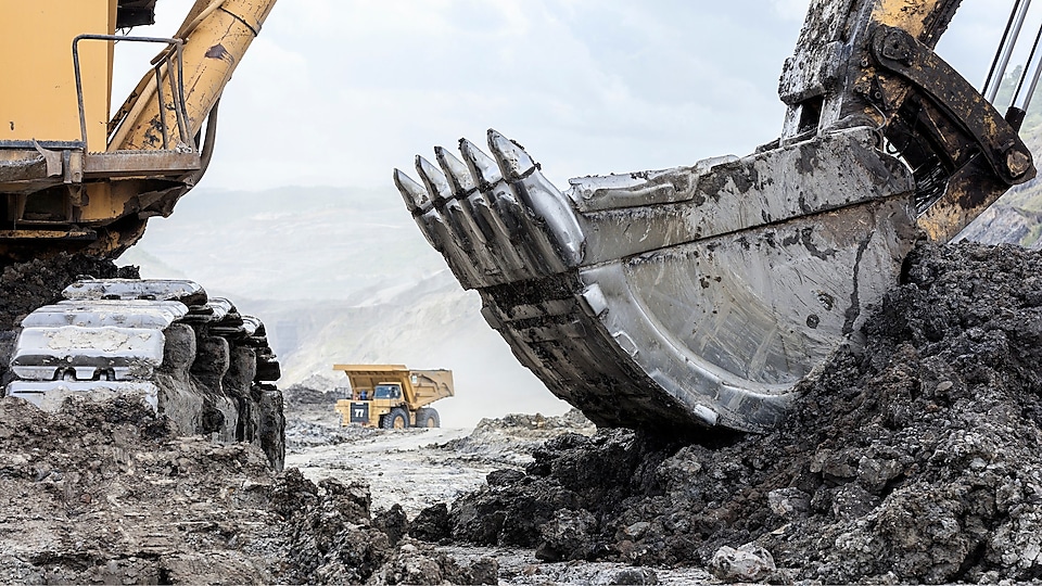 Tracked Excavator loading sediment into Articulated Dump Truck in quarry Supporting Image: Tracked Excavator and dump truck in the background