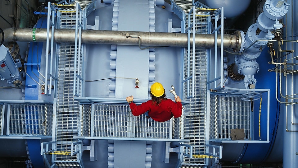 Worker inspecting valve at power station