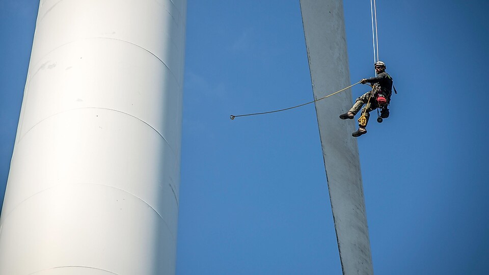 A maintenance crew member working at height on a wind turbine