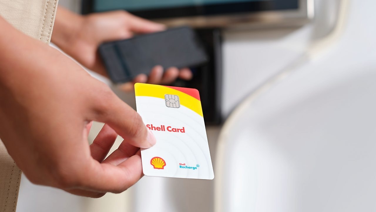 Shell customer holding a Shell card at an electric vehicle charging post