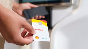 Shell customer holding a Shell card at an electric vehicle charging post