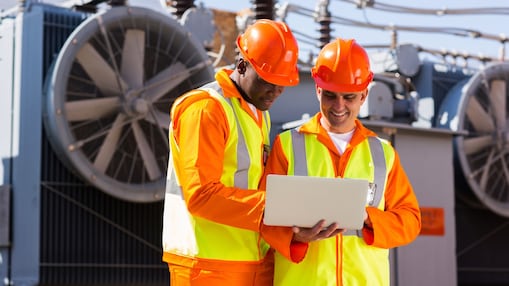 2 builders in hardhats staring at a laptop
