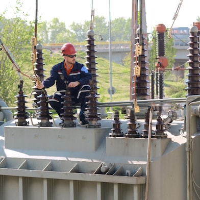 Engineer in hard hart sitting on Transformer