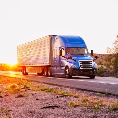 Blue truck driving down a road