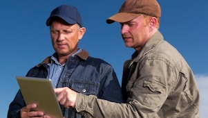 Two farmers reviewing information on tablet