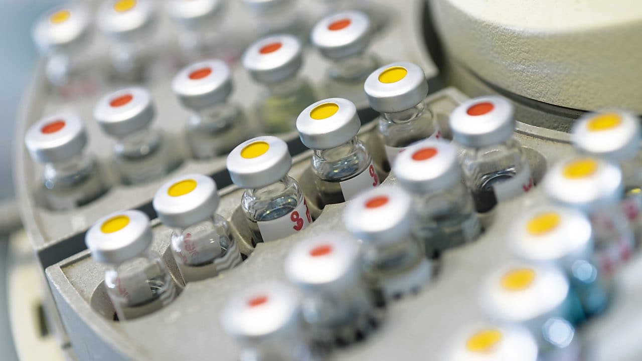 Rows of medicine vials sitting in a holder, some with red dots on the lid, and some with yellow dots on the lid
