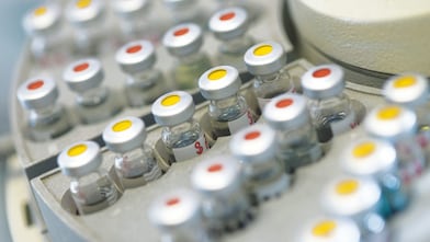 Rows of medicine vials sitting in a holder, some with red dots on the lid, and some with yellow dots on the lid