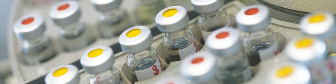 Rows of medicine vials sitting in a holder, some with red dots on the lid, and some with yellow dots on the lid