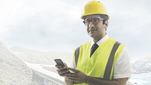 Man wearing a yellow safety helmet holding a phone