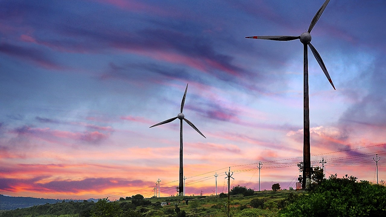 Two wind turbines with pink, purple and blue sunset background.