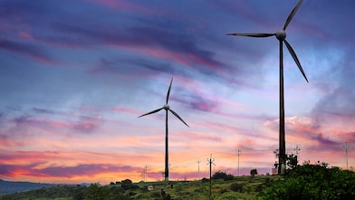 Two wind turbines with pink, purple and blue sunset background.