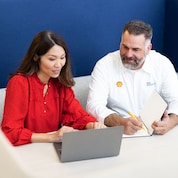 Man wearing Shell branded shirt interacting with Women wearing a red shirt.