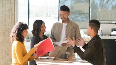 Two males and two femails interacting in a kitchen environment.