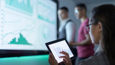 Women interacting with graphs on an iPad screen.