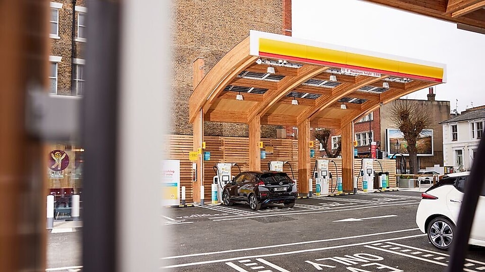Modern electric vehicle charging station with wooden architecture and multiple charging units, with a car parked for charging.