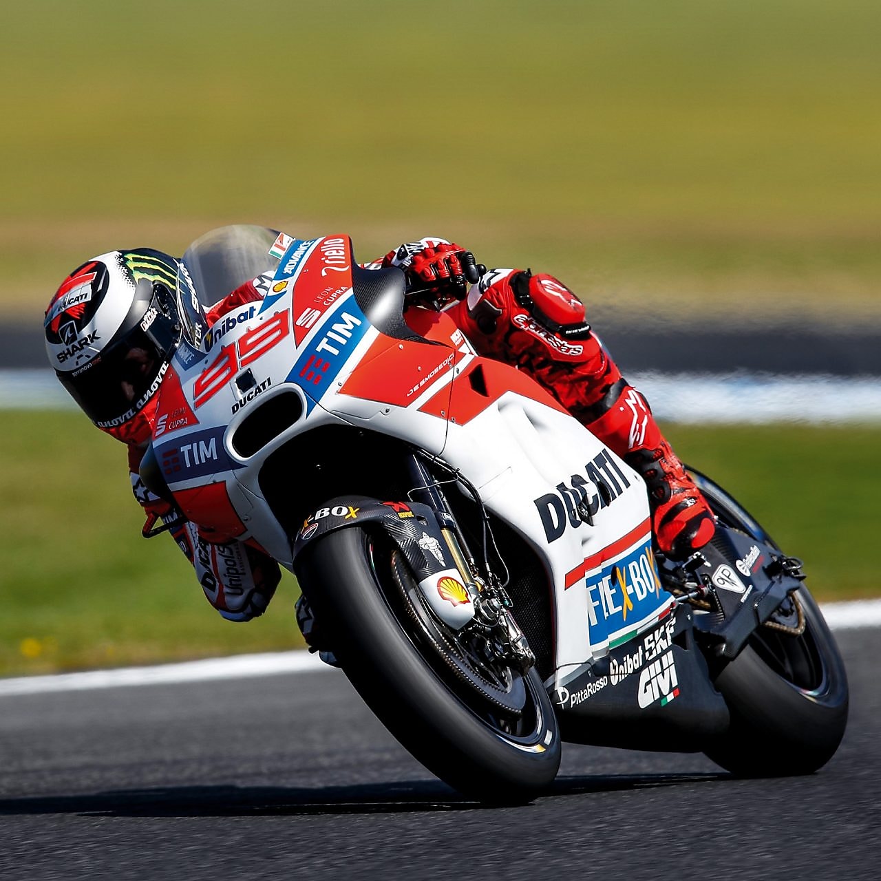 ducati superbike with rider cornering at speed on a racetrack