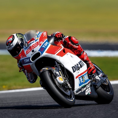 ducati superbike with rider cornering at speed on a racetrack