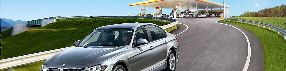 Silver BMW on the road with Shell station in background