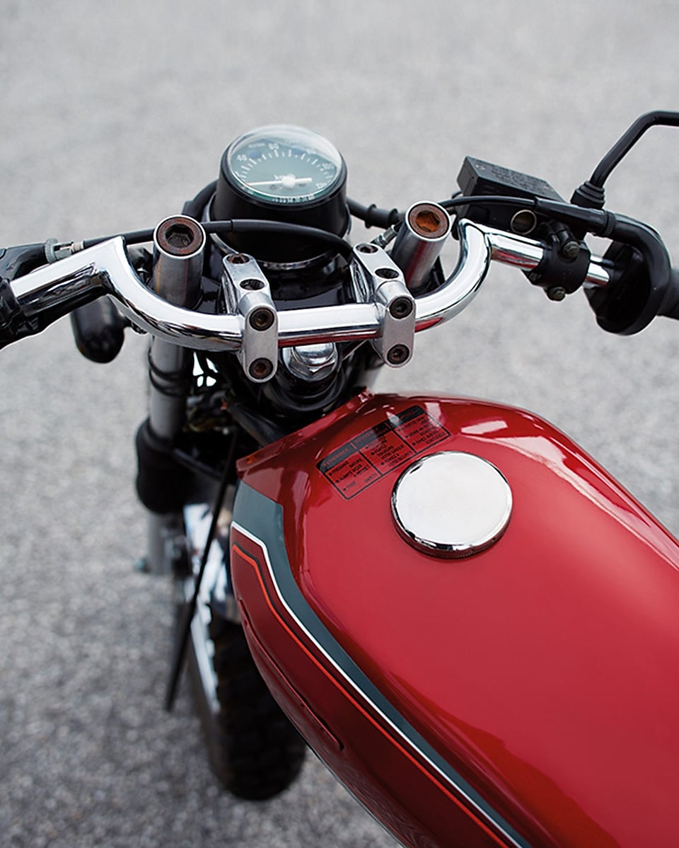 red motorcycle petrol tank with front wheel, handle bars, and speedometer