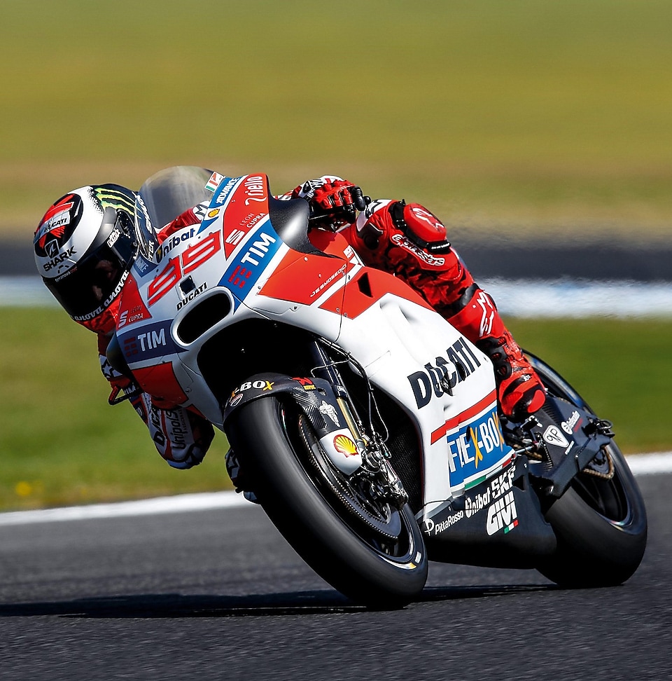 ducati superbike with rider cornering at speed on a racetrack