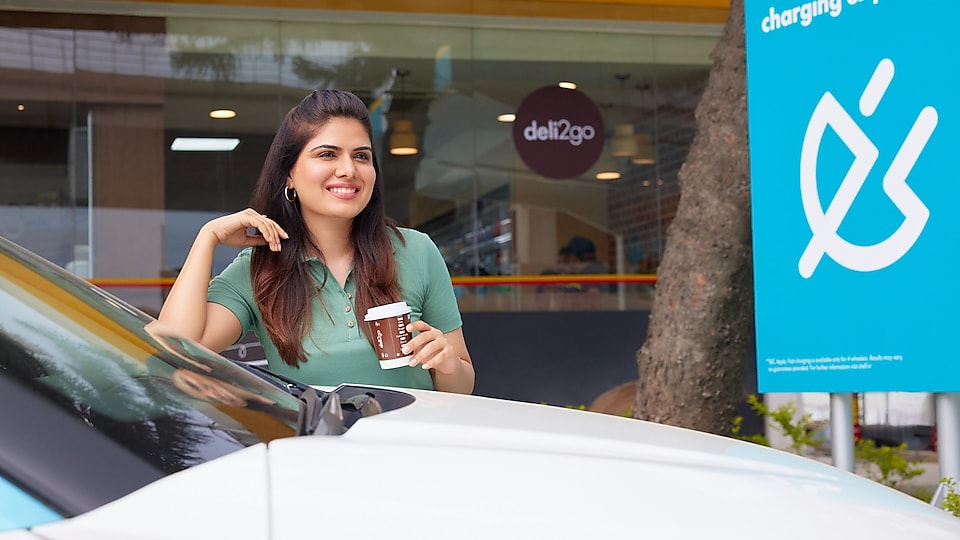 Woman holding a coffe cup near car