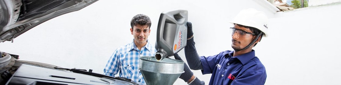 mechanic replacing engine oil as customer look son