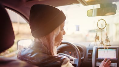 A young woman checks the instructions displayed on her car's built-in navigation screen